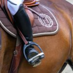 person in white cowboy hat riding brown horse during daytime