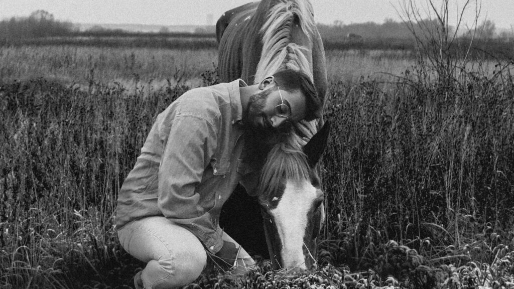 man in jacket sitting on grass field