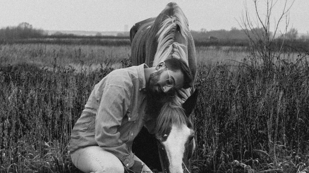 grayscale photo of woman in jacket sitting on grass field