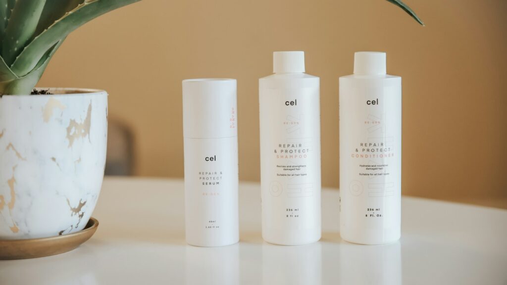 three bottles of lotion sitting on a table next to a potted plant