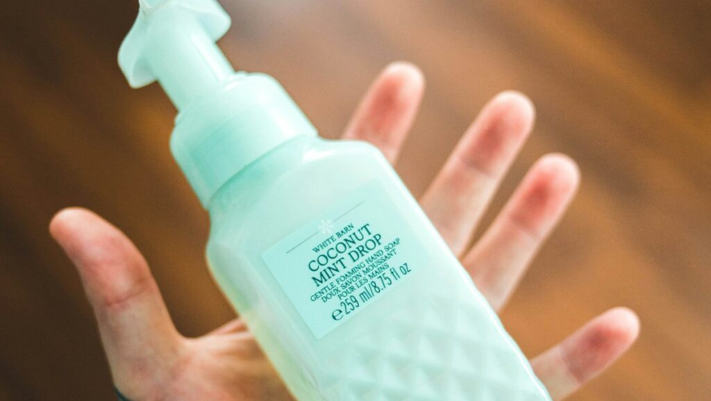 person holding white plastic pump bottle