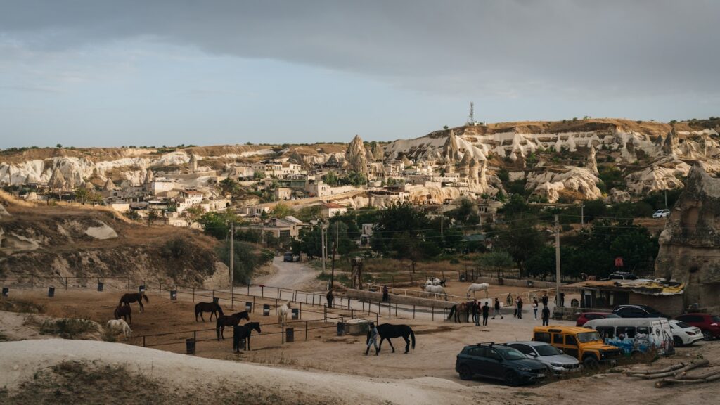 A group of horses and cars in a parking lot