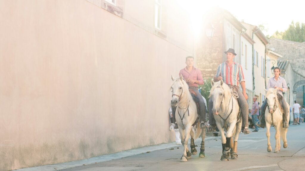 three men riding horses near white concrete building during daytime