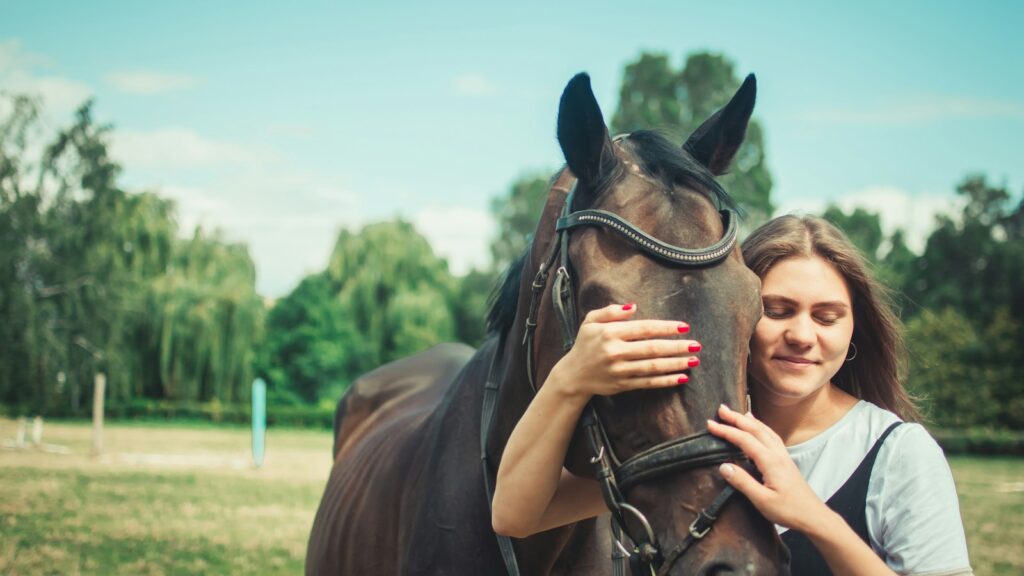woman in black tank top holding brown horse during daytime