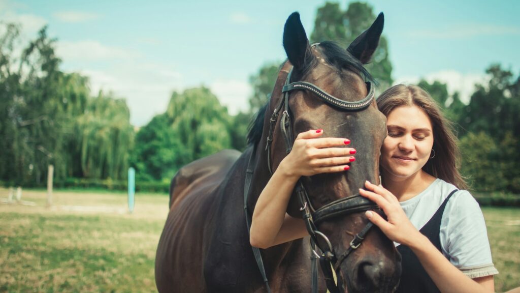 woman in black tank top holding brown horse during daytime