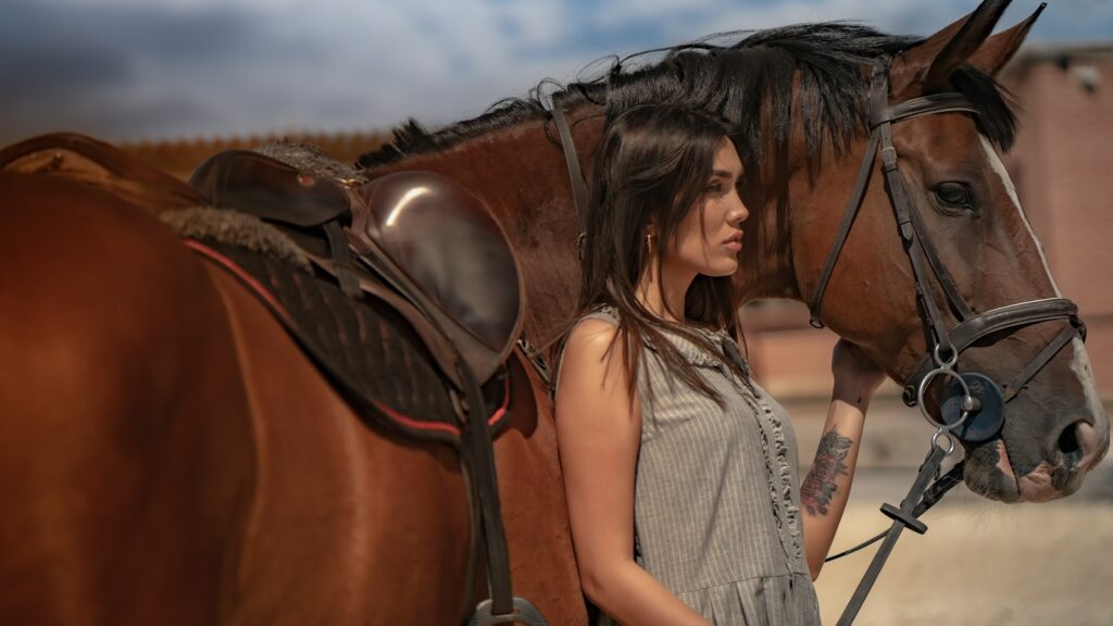 a woman standing next to a brown horse