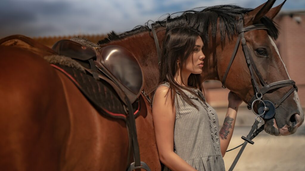 a woman standing next to a brown horse