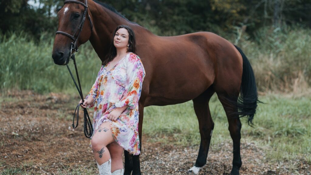 A woman standing next to a brown horse