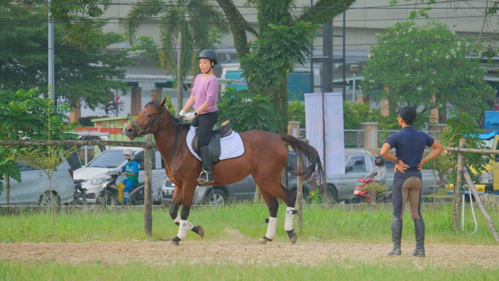 man in white shirt riding brown horse during daytime