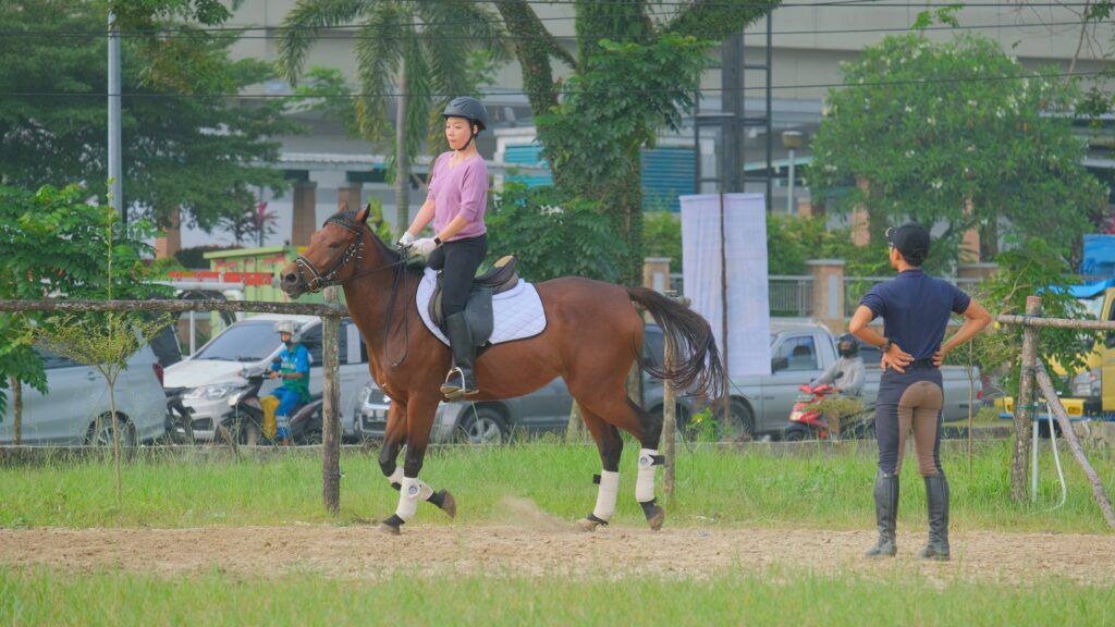 man in white shirt riding brown horse during daytime