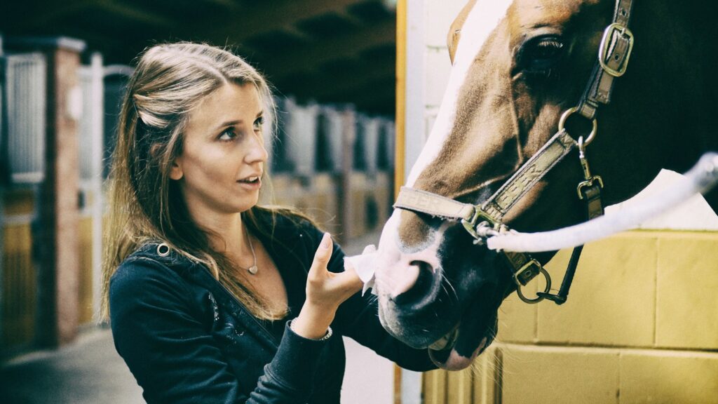 woman in black long sleeve shirt holding white horse head during daytime