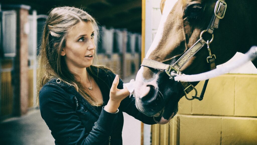 woman in black long sleeve shirt holding white horse head during daytime