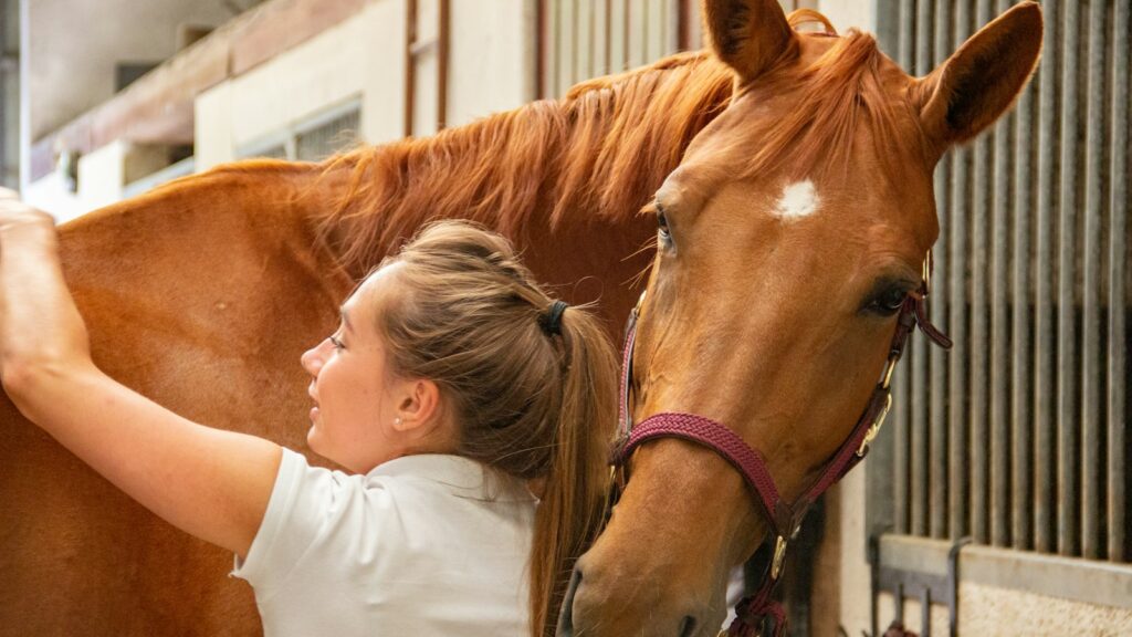 woman in white crew neck t-shirt standing beside brown horse during daytime