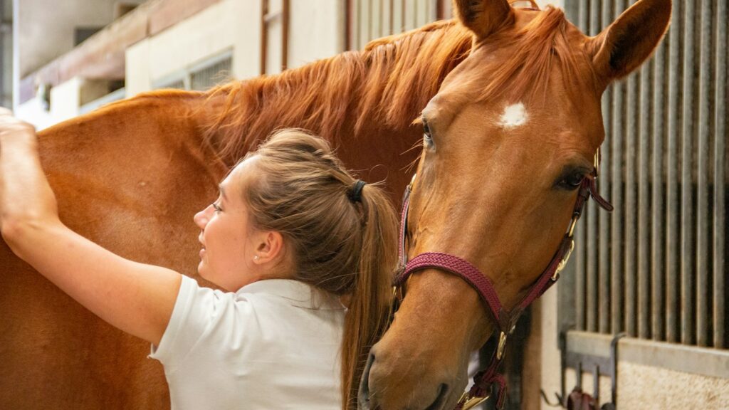 woman in white crew neck t-shirt standing beside brown horse during daytime