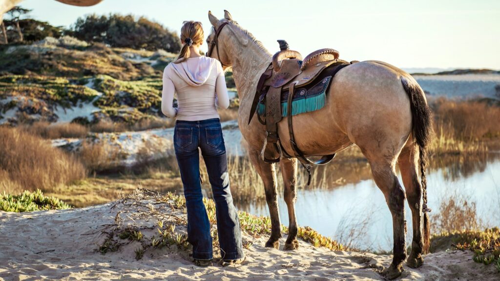 woman stands near a horse