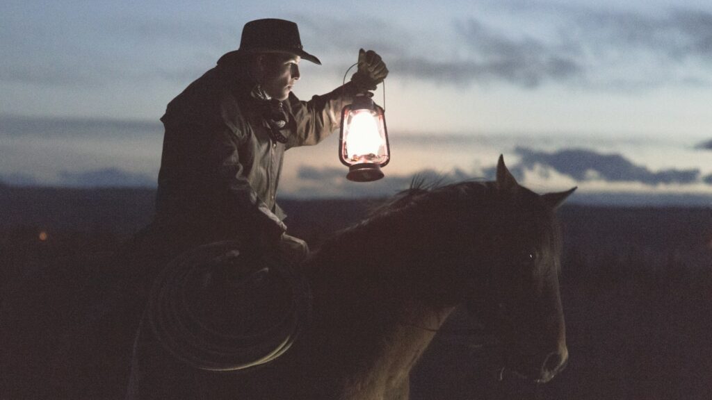 man riding horse holding lantern