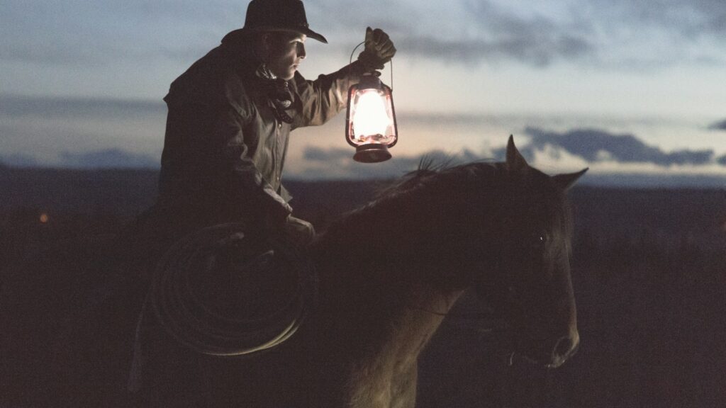 man riding horse holding lantern