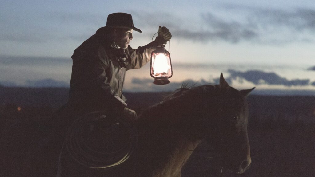man riding horse holding lantern