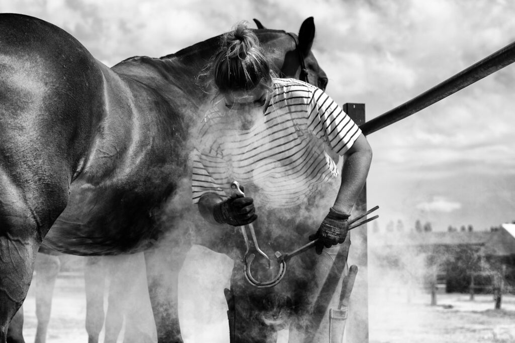 Grayscale photo of farrier by a horse