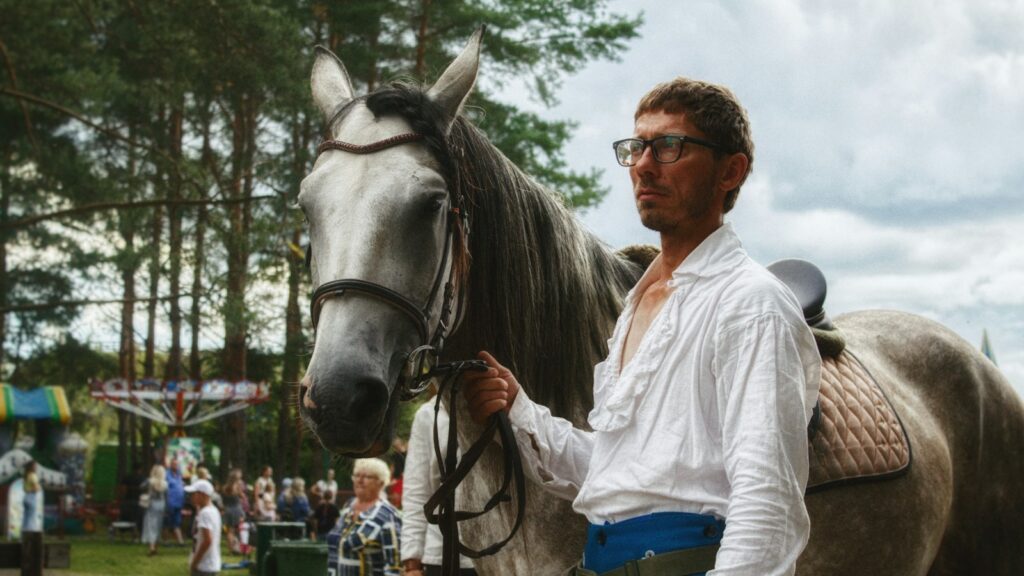 a man standing next to a brown horse