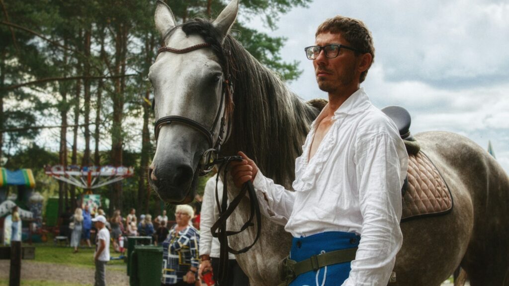 a man standing next to a brown horse