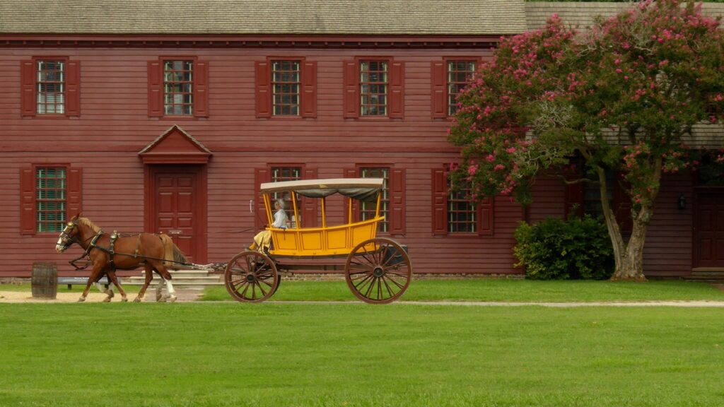 brown horse with yellow carriage beside red concrete house