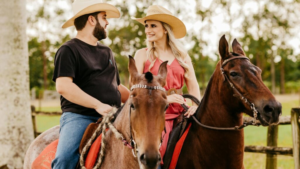 woman in black shirt and blue denim jeans wearing brown cowboy hat riding brown horse during