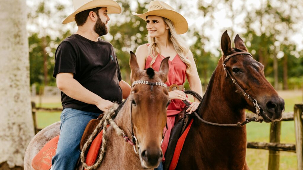 woman in black shirt and blue denim jeans wearing brown cowboy hat riding brown horse during
