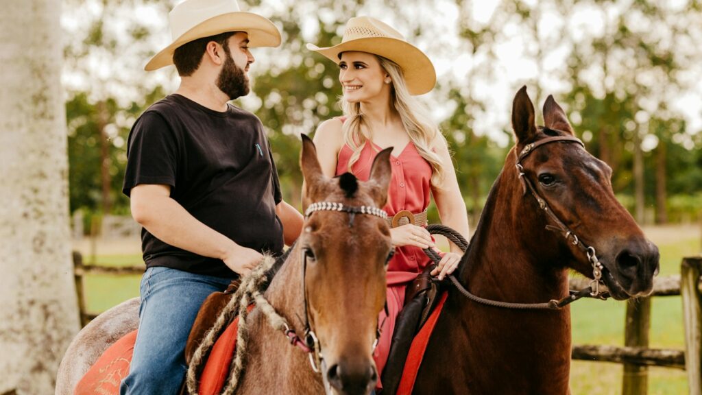 woman in black shirt and blue denim jeans wearing brown cowboy hat riding brown horse during