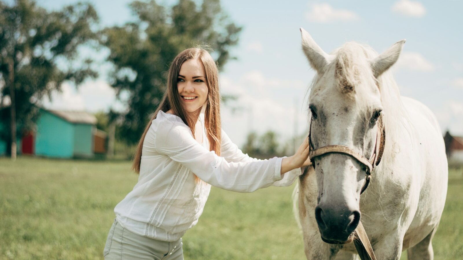 woman in white long sleeve shirt riding white horse during daytime