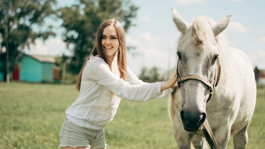 woman in white long sleeve shirt riding white horse during daytime