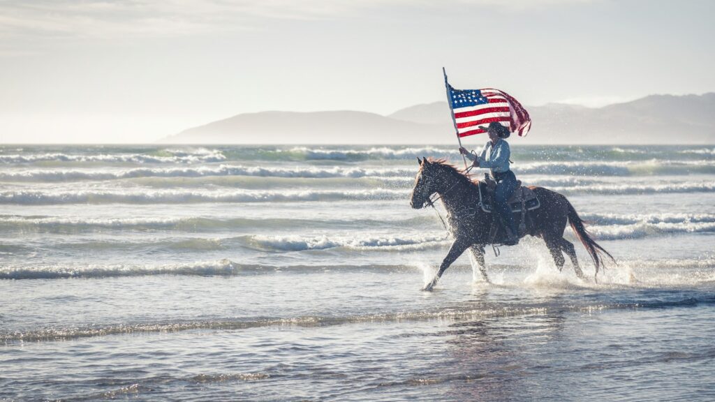 a man riding a horse with an american flag on its back