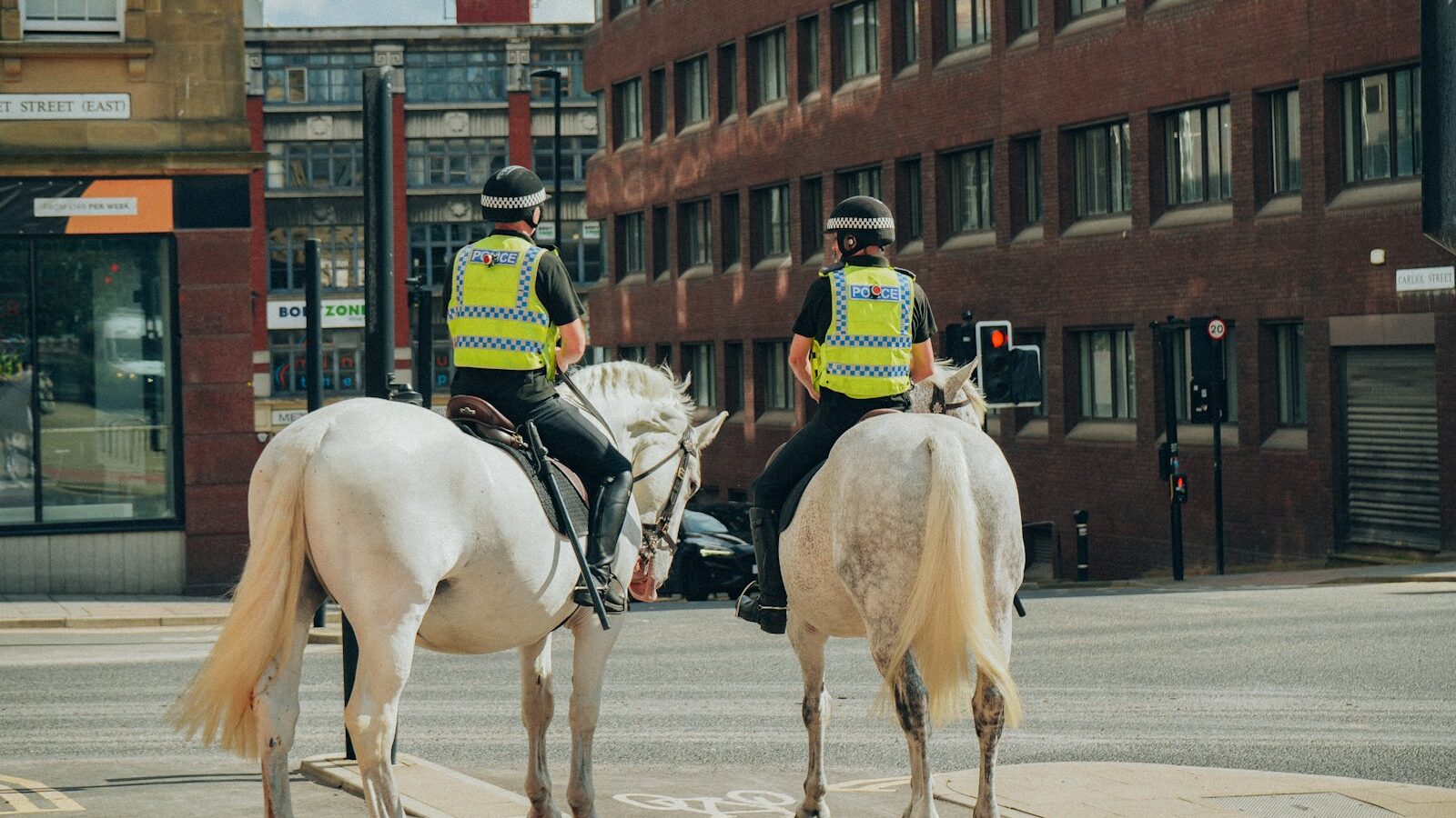 two police officers riding horses on a city street