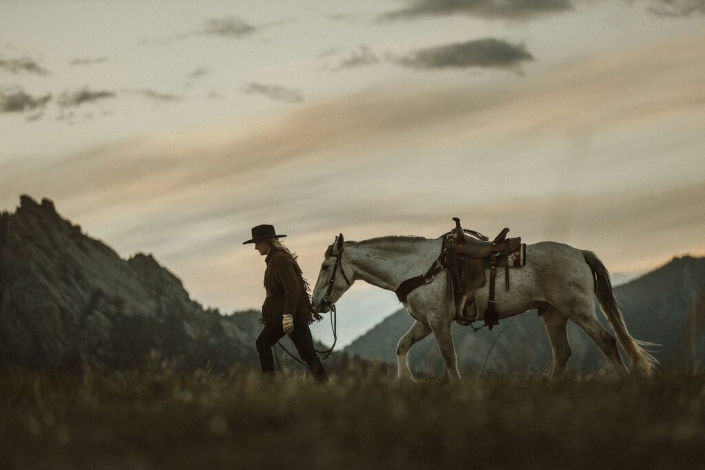 Cowboy standing beside white horse during daytime