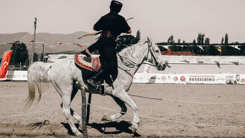 Horseback archer in action at outdoor event, displaying traditional skills.