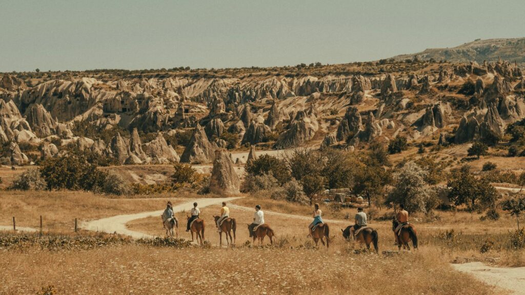 Riders traversing the breathtaking rock formations of Cappadocia on horseback.
