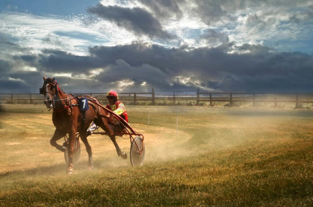 Dramatic scene of harness racing in Genêts, Normandie, France, capturing speed and energy.