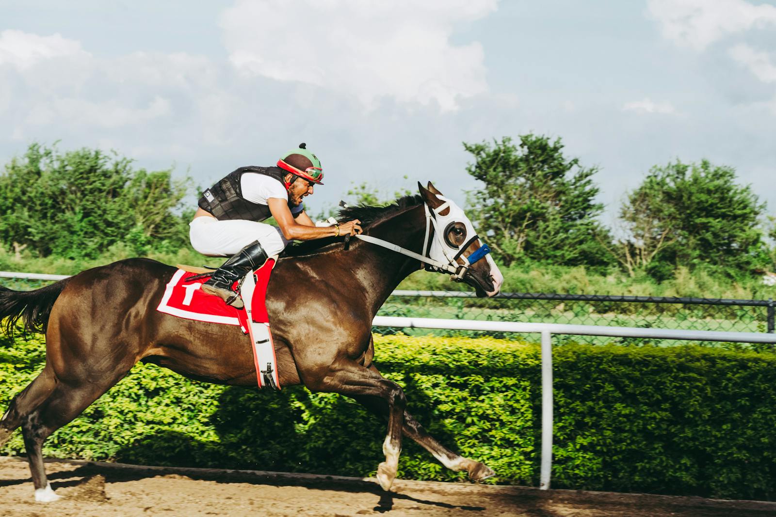 A thrilling action shot of a jockey riding a horse at full speed during a race on a sunny day.