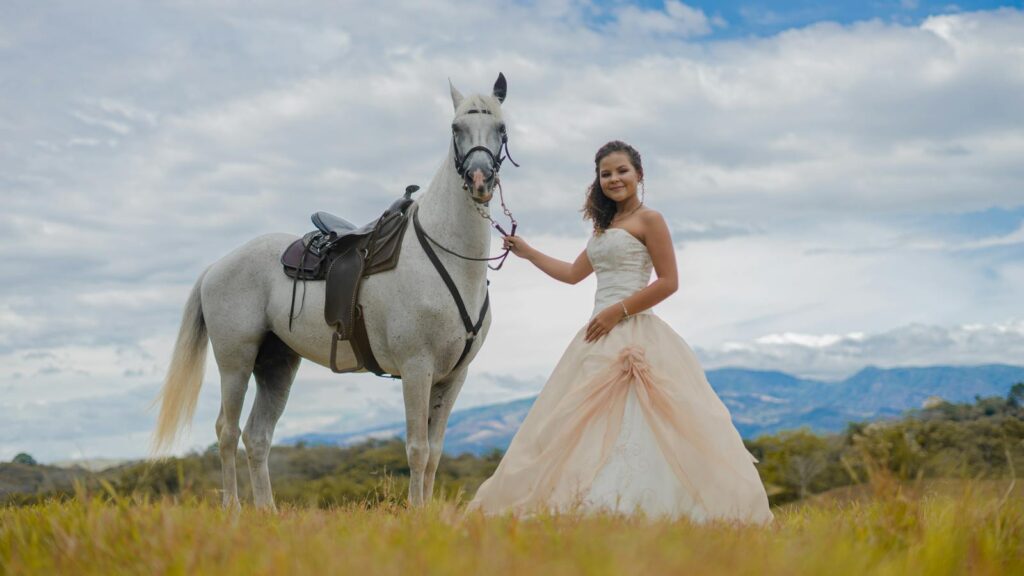 A smiling woman in a wedding dress poses with a horse in rural Costa Rica.