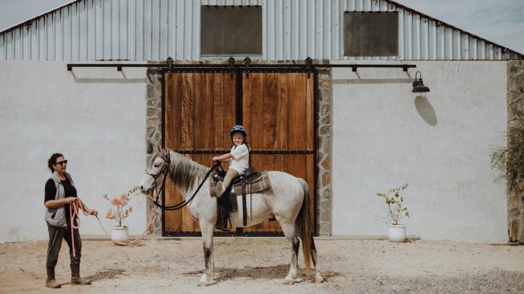 A young girl rides a horse with her mother nearby at a farm in San Juan del Rancho, Mexico.