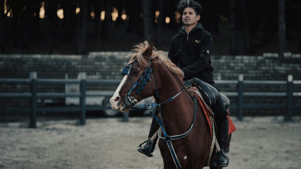 A man riding a horse in an equestrian arena, showcasing skilled horsemanship.