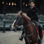 A man riding a horse in an equestrian arena, showcasing skilled horsemanship.