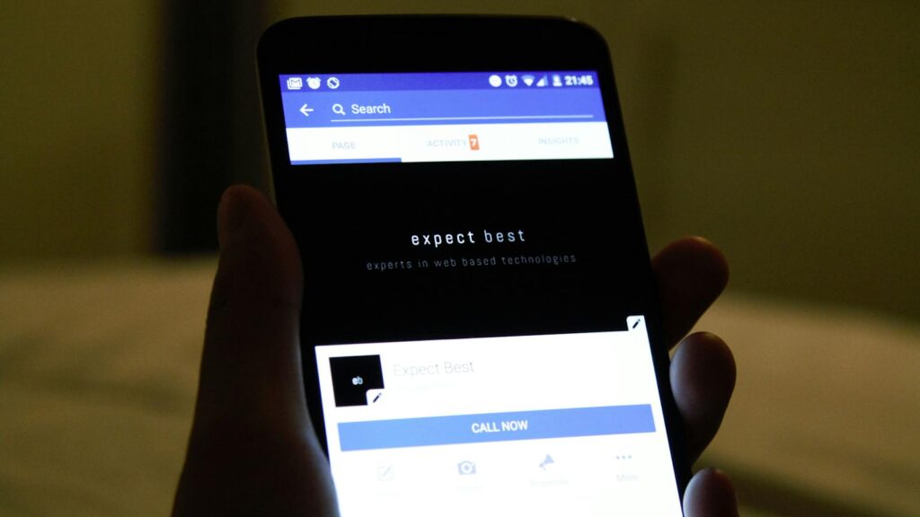 Close-up of a hand holding a smartphone showing a social media application screen.