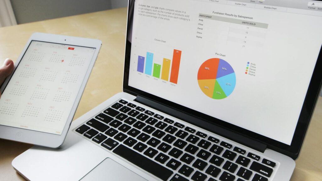 Laptop displaying charts and graphs with tablet calendar for data analysis and planning.