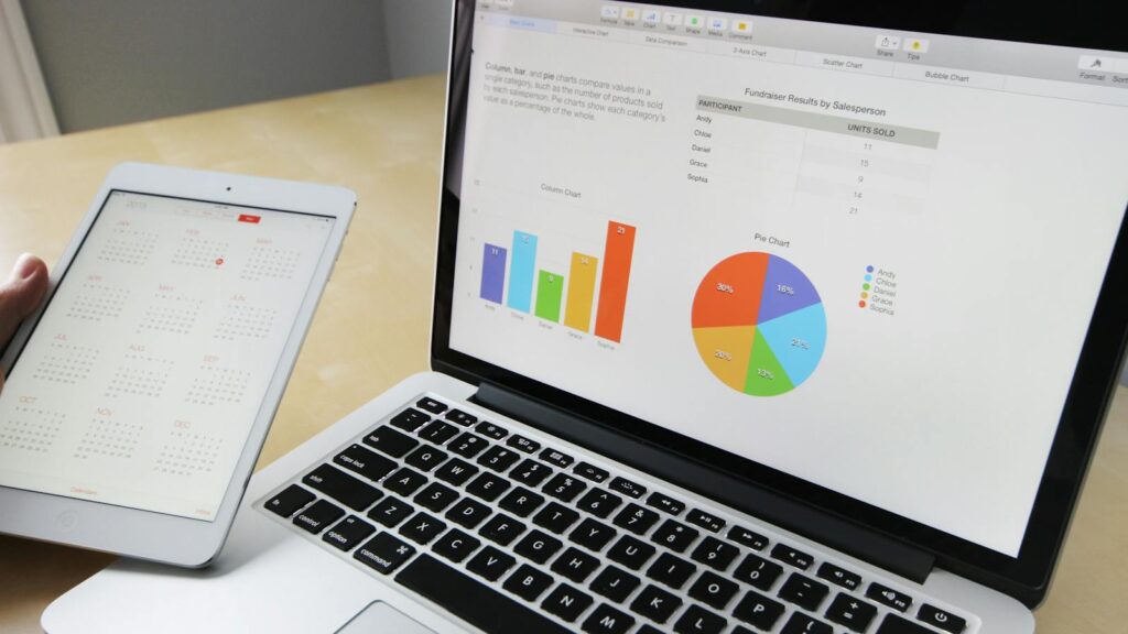 Laptop displaying charts and graphs with tablet calendar for data analysis and planning.