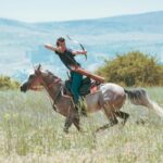 A horseback archer practicing in a lush green field in Konya, Türkiye.