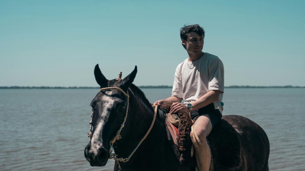 A man riding a horse near the serene Chascomús Lake in Argentina.