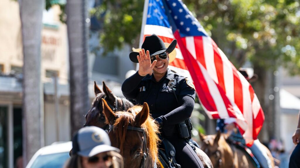 Smiling police officer on horseback during patriotic parade in Miami, Florida.