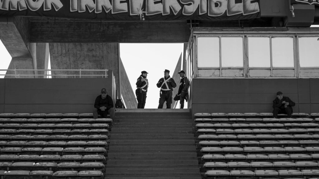 Black and white photo of a stadium grandstand in Córdoba, Argentina, with police presence.