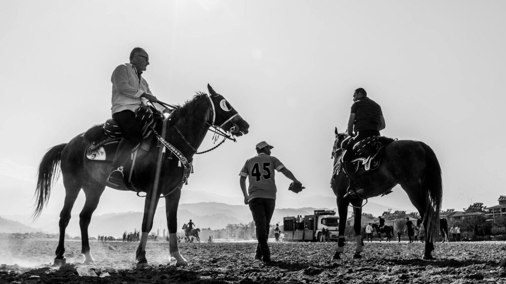 Black and white photo of horse riders and their horses during a daytime equestrian event in Salihli, Türkiye.